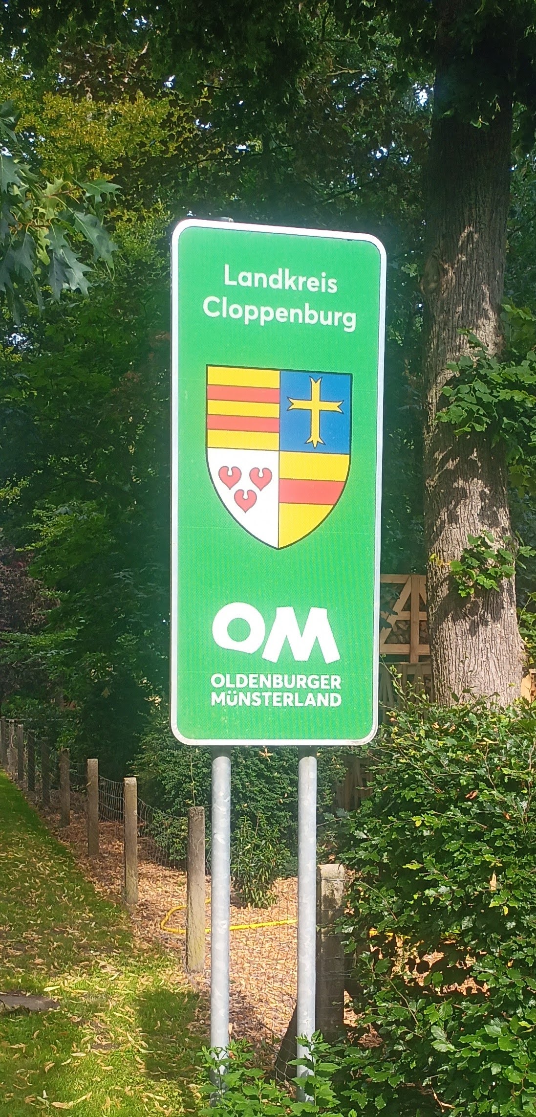 Schild mit Logo Oldenburger Münsterland und dem Wappen des Landkreises Cloppenburg