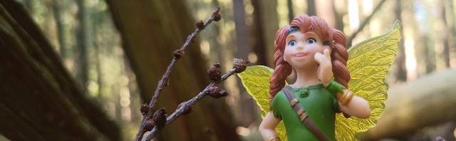 Miniaturelfe auf einem Baumtamm im Wald