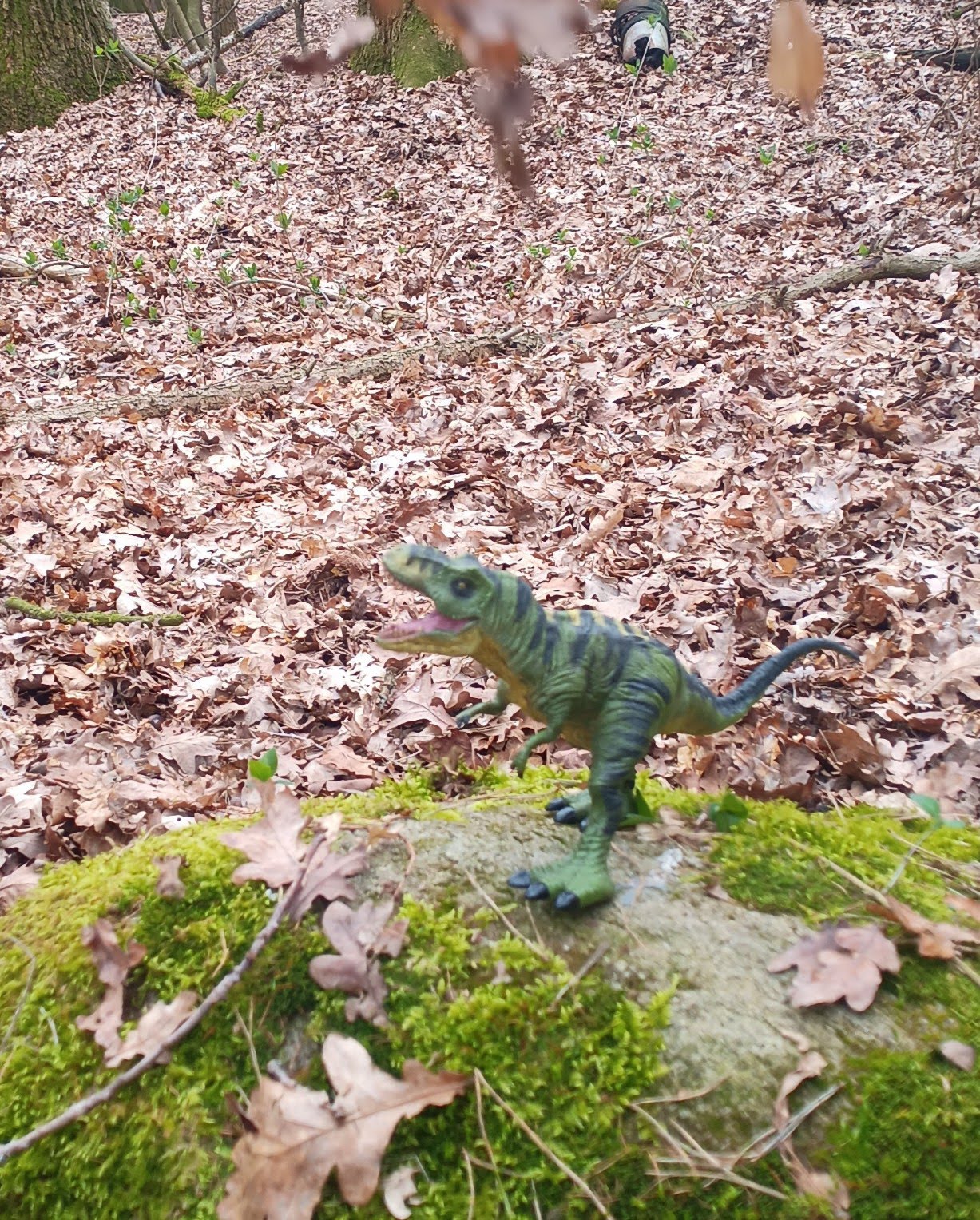 Dinofigur auf bemoostem Stein